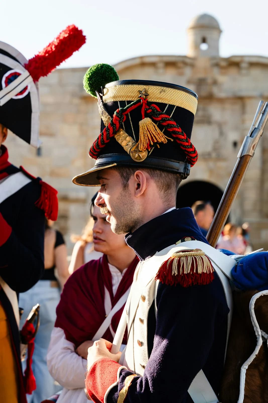 Soldiers in full ceremonial dress with sashes, ribbons and rifles on parade